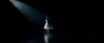 Movie still from “Black Swan” (2010), directed by Darren Aronofsky – A woman in a white dress standing in a dark room; Wide shot, Low angle