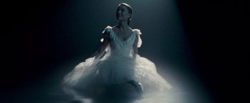 Movie still from “Black Swan” (2010), directed by Darren Aronofsky – A woman in a white dress sitting on the ground; Medium shot, Low angle