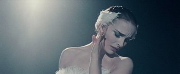 Movie still from “Black Swan” (2010), directed by Darren Aronofsky – A woman in a white dress with a white feather around her head; Close Up shot, Low angle