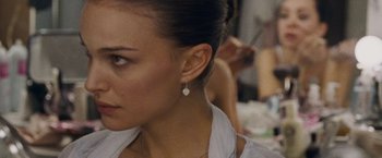 Movie still from “Black Swan” (2010), directed by Darren Aronofsky – A person wearing a white shirt and earrings; Close Up shot, Over the shoulder angle