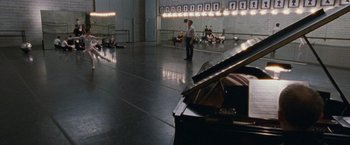 Movie still from “Black Swan” (2010), directed by Darren Aronofsky – A man standing next to a grand piano in a room; Wide shot, High angle