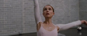 Movie still from “Black Swan” (2010), directed by Darren Aronofsky – A woman in a white leotard is standing in front of a brick wall; Close Up shot, Low angle