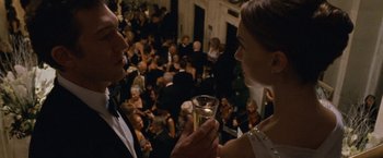 Movie still from “Black Swan” (2010), directed by Darren Aronofsky – A man and a woman holding a glass of champagne in front of a crowd; Medium shot, Over the shoulder angle