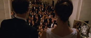 Movie still from “Black Swan” (2010), directed by Darren Aronofsky – A group of people in formal wear standing in a room; Medium shot, Over the shoulder angle