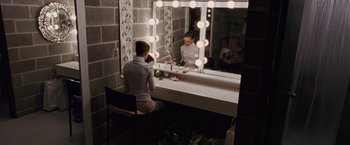 Movie still from “Black Swan” (2010), directed by Darren Aronofsky – A woman sitting in front of a mirror in a room; Wide shot, High angle