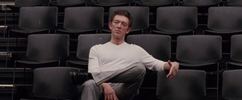 Movie still from “Black Swan” (2010), directed by Darren Aronofsky – A man sitting on a chair with his eyes closed; Medium shot, Low angle