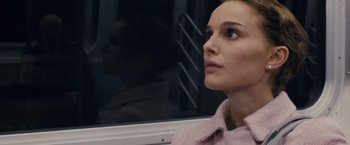 Movie still from “Black Swan” (2010), directed by Darren Aronofsky – A person sitting on a train; Close Up shot, Over the shoulder angle