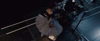 Movie still from “Black Swan” (2010), directed by Darren Aronofsky – A woman in a black and white dress is standing on a step; Wide shot, Low angle
