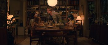 Movie still from “Black Widow” (2021), directed by Cate Shortland – A group of people sitting at a table with food; Wide shot, High angle