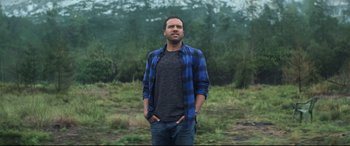 Movie still from “Black Widow” (2021), directed by Cate Shortland – A man standing in front of some trees; Medium shot, Low angle