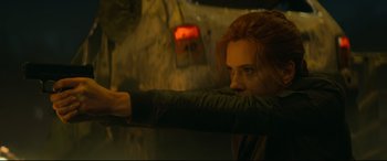 Movie still from “Black Widow” (2021), directed by Cate Shortland – A person holding a gun; Medium shot, Low angle