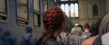 Movie still from “Black Widow” (2021), directed by Cate Shortland – A woman with red hair is standing in front of a train; Close Up shot, Over the shoulder angle