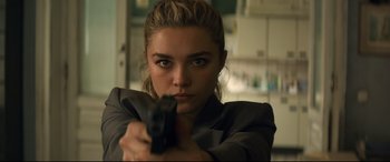 Movie still from “Black Widow” (2021), directed by Cate Shortland – A beautiful young lady holding a gun while wearing a suit; Close Up shot, Over the shoulder angle