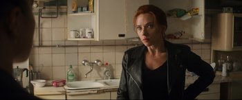 Movie still from “Black Widow” (2021), directed by Cate Shortland – A woman standing in front of a sink in a kitchen; Medium shot, Over the shoulder angle