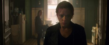 Movie still from “Black Widow” (2021), directed by Cate Shortland – A woman in a black leather jacket looking at the camera; Medium shot, Over the shoulder angle