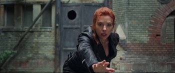 Movie still from “Black Widow” (2021), directed by Cate Shortland – A woman in a black leather jacket is reaching out her hand; Medium shot, Low angle