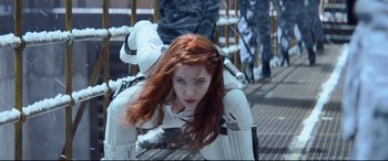 Movie still from “Black Widow” (2021), directed by Cate Shortland – A red haired woman in a white suit is laying on the ground; Medium shot, Low angle
