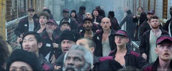 Movie still from “Black Widow” (2021), directed by Cate Shortland – A group of men standing next to each other in the street; Wide shot, High angle