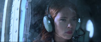 Movie still from “Black Widow” (2021), directed by Cate Shortland – A woman wearing headphones while sitting in a car; Close Up shot, Low angle