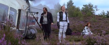 Movie still from “Black Widow” (2021), directed by Cate Shortland – A man and a woman standing next to each other in a field; Wide shot, Low angle