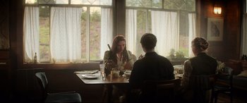 Movie still from “Black Widow” (2021), directed by Cate Shortland – Two people sitting at a table in front of a window; Medium shot, Over the shoulder angle