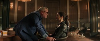 Movie still from “Black Widow” (2021), directed by Cate Shortland – A man and a woman sitting on a chair; Medium shot, Over the shoulder angle