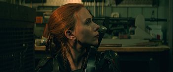 Movie still from “Black Widow” (2021), directed by Cate Shortland – A woman with red hair is holding a microphone in her mouth; Close Up shot, Low angle