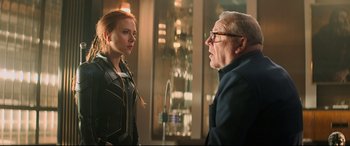Movie still from “Black Widow” (2021), directed by Cate Shortland – A man and a woman are standing next to each other; Medium shot, Over the shoulder angle