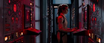 Movie still from “Black Widow” (2021), directed by Cate Shortland – A woman standing next to a bunch of computer equipment; Medium shot, Over the shoulder angle