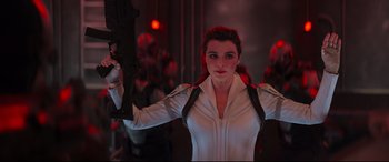 Movie still from “Black Widow” (2021), directed by Cate Shortland – A woman holding a gun while wearing a white jacket; Medium shot, Low angle