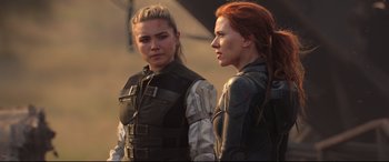 Movie still from “Black Widow” (2021), directed by Cate Shortland – Two women standing next to each other on a field; Medium shot, Over the shoulder angle