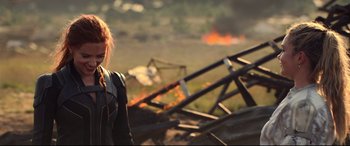 Movie still from “Black Widow” (2021), directed by Cate Shortland – A woman standing in front of a fire; Medium shot, Over the shoulder angle