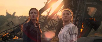 Movie still from “Black Widow” (2021), directed by Cate Shortland – Two women standing next to each other in front of a metal structure; Medium shot, Low angle