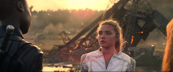 Movie still from “Black Widow” (2021), directed by Cate Shortland – A woman standing in front of an amusement park ride; Close Up shot, Over the shoulder angle