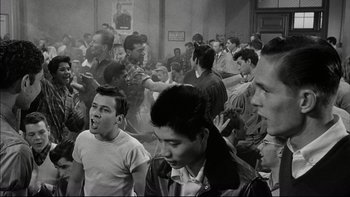 Movie still from “Blackboard Jungle” (1955), directed by Richard Brooks – Black and white photograph of a group of young men in a room; Medium shot, High angle