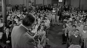 Movie still from “Blackboard Jungle” (1955), directed by Richard Brooks – A man is speaking to a group of people; Wide shot, High angle