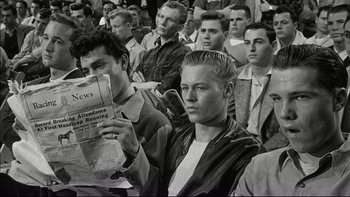 Movie still from “Blackboard Jungle” (1955), directed by Richard Brooks – Black and white photograph of a crowd of young men holding news papers; Medium shot, Low angle