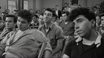 Movie still from “Blackboard Jungle” (1955), directed by Richard Brooks – Black and white photograph of men sitting in front of a crowd; Medium shot, Over the shoulder angle