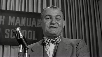Movie still from “Blackboard Jungle” (1955), directed by Richard Brooks – An old photo of a man in a suit and tie; Close Up shot, Low angle