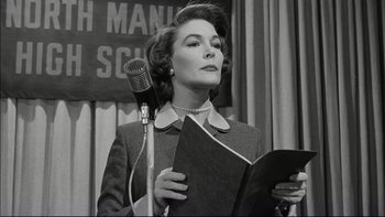 Movie still from “Blackboard Jungle” (1955), directed by Richard Brooks – An old photo of a woman holding a book and a microphone; Medium shot, Low angle