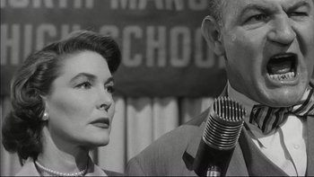 Movie still from “Blackboard Jungle” (1955), directed by Richard Brooks – An older man and a woman standing next to each other with a microphone; Close Up shot, Low angle