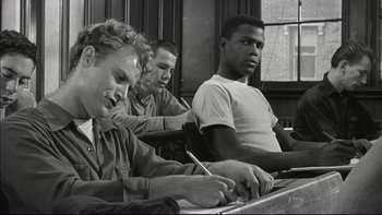 Movie still from “Blackboard Jungle” (1955), directed by Richard Brooks – A group of men sitting at a table working on papers; Medium shot, High angle