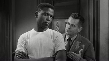 Movie still from “Blackboard Jungle” (1955), directed by Richard Brooks – A black and white photo of a man and a white man; Medium shot, Over the shoulder angle