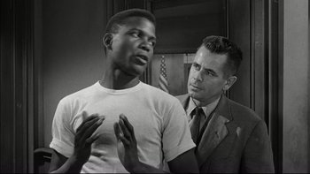 Movie still from “Blackboard Jungle” (1955), directed by Richard Brooks – A black and white photo of a man and a white man; Medium shot, Over the shoulder angle