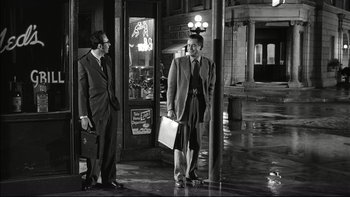 Movie still from “Blackboard Jungle” (1955), directed by Richard Brooks – A man and a woman standing next to each other on the sidewalk; Wide shot, Low angle
