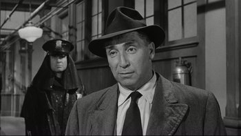 Movie still from “Blackboard Jungle” (1955), directed by Richard Brooks – A man wearing a hat and a suit and tie standing in front of another man; Close Up shot, Low angle