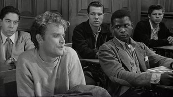 Movie still from “Blackboard Jungle” (1955), directed by Richard Brooks – A group of men sitting next to each other in a room; Medium shot, Over the shoulder angle