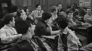 Movie still from “Blackboard Jungle” (1955), directed by Richard Brooks – Black and white photograph of a group of young men sitting in a classroom; Medium shot, High angle