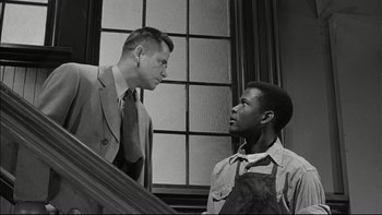 Movie still from “Blackboard Jungle” (1955), directed by Richard Brooks – A man and a man wearing an apron talking to each other; Medium shot, Low angle