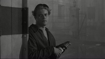 Movie still from “Blackboard Jungle” (1955), directed by Richard Brooks – A black and white photo of a man holding a bottle; Close Up shot, Over the shoulder angle
